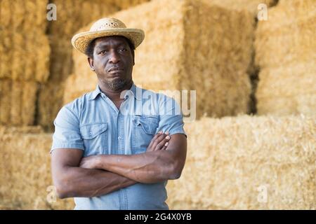 Selbstbewusster afroamerikanischer Bauer, der in der Nähe des Strohstapels steht Stockfoto