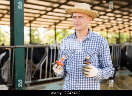 Landwirt mit Spritze und Medizin in den Händen auf dem Milchviehbetrieb Stockfoto