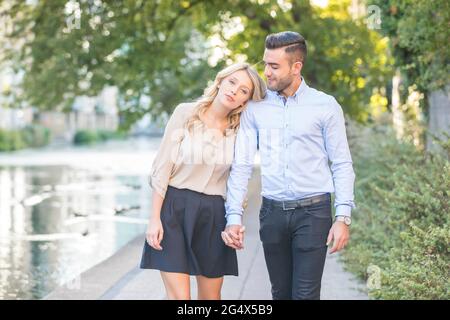 Frau, die sich auf die Schulter des Freundes lehnt, während sie auf der Promenade läuft Stockfoto