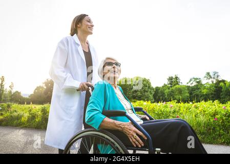 Lächelnde ältere Frau mit Hausmeister im öffentlichen Park Stockfoto