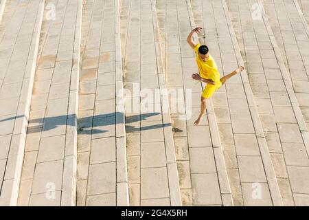Junger Mann, der an sonnigen Tagen auf der Treppe tanzt Stockfoto