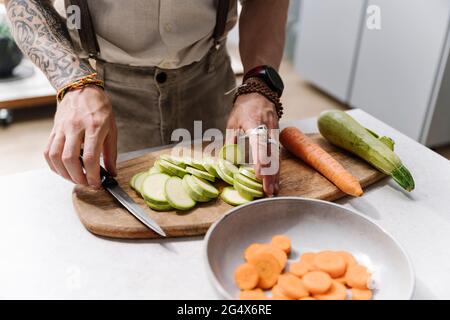 Mann schneidet Zucchini in der Küche zu Hause Stockfoto