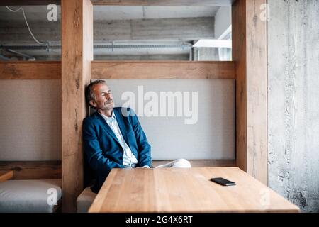 Senior Businessman ruht sich aus, während er im Büro sitzt Stockfoto