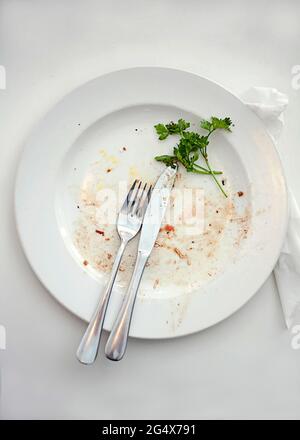 Teller mit Essensresten und Besteck auf dem Tisch Stockfoto