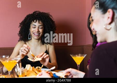 Lächelnde Frau mit Vorspeise mit Freunden im Restaurant Stockfoto