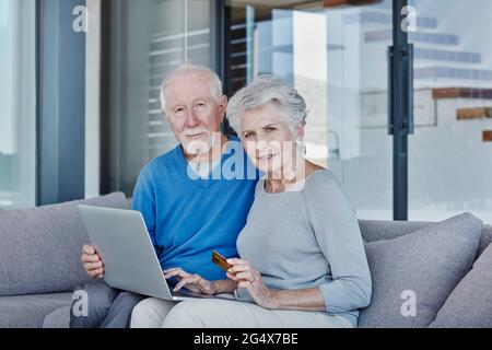 Ältere Paare, die zu Hause einen Laptop verwenden, während sie online einkaufen Stockfoto