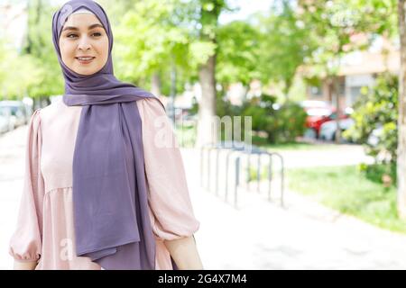 Junge Frau, die Hijab trägt, schaut weg, während sie im Park steht Stockfoto