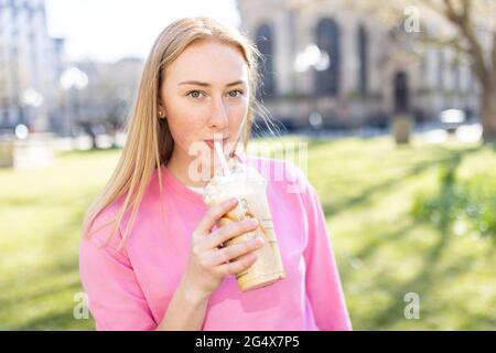 Schöne Frau, die im öffentlichen Park Milchshake trinkt Stockfoto
