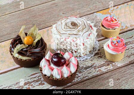 Mini-Vanillekuchen mit getrockneten Kokosnusschips und Schlagsahne dekoriert. Neben Mini-Pasteten und Mini-Sablée-Pasteten mit Schlagsahne. Stockfoto