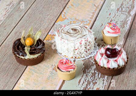 Mini-Vanillekuchen mit getrockneten Kokosnusschips und Schlagsahne dekoriert. Neben Mini-Pasteten und Mini-Sablée-Pasteten. Stockfoto