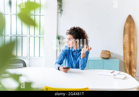 Geschäftsfrau mit Mobiltelefon schaut im kreativen Büro weg Stockfoto