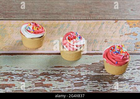 Drei Mini-Sablée-Pasteten mit Schlagsahne auf einem Holztisch. Stockfoto