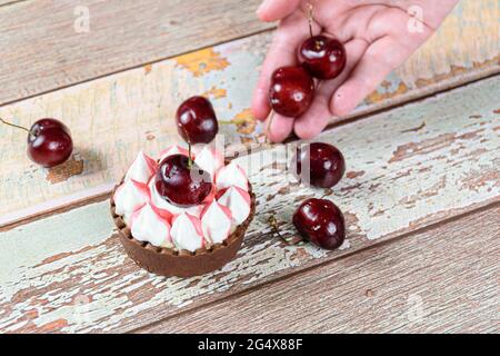Schokoladen-Mini-Pie mit Schokoladenganache, gekrönt mit Schlagsahne und Kirsche. Konditorei mit Kirschen dekorieren. Stockfoto