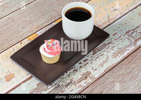 Mini-Torte mit Sablée-Gebäck und Schlagsahne, neben einer Tasse Kaffee. Stockfoto