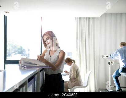 Junge professionelle Frau, die im Büro Dokumente ansieht Stockfoto