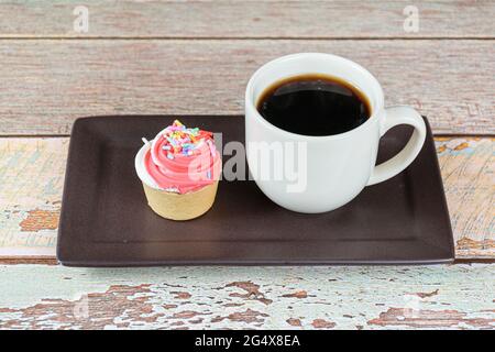 Nahaufnahme einer Mini-Pie mit Sablee-Gebäck und Schlagsahne, neben einer Tasse Kaffee. Stockfoto