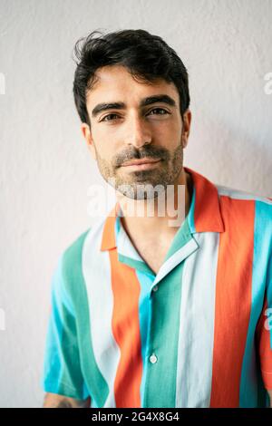 Hübscher Mann, der vor einer weißen Wand steht Stockfoto