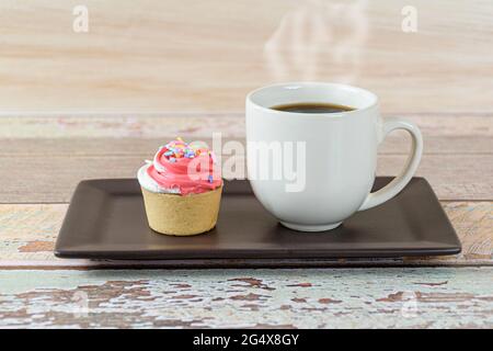 Nahaufnahme einer Mini-Pie mit Sablee-Gebäck und Schlagsahne, neben einer Tasse Kaffee (Seitenansicht). Stockfoto