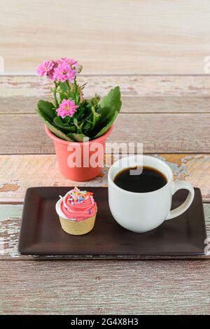 Nahaufnahme einer Mini-Pie mit Sablee-Gebäck und Schlagsahne, neben einer Tasse Kaffee und einer Pflanze. Stockfoto