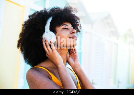 Entspannte Afro-Frau, die über Kopfhörer Musik hört Stockfoto