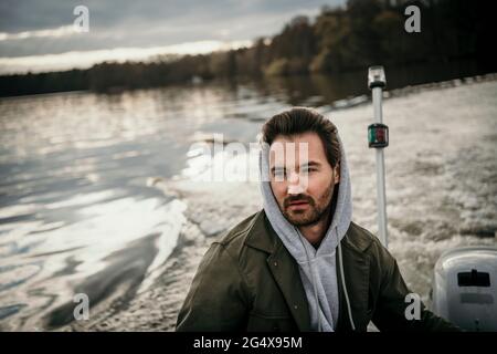 Ein hübscher Mann mit Kapuze auf der Fahrt im Boot auf dem See Stockfoto