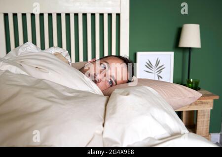 Mann, der zu Hause im Bett liegt, kontempliert Stockfoto