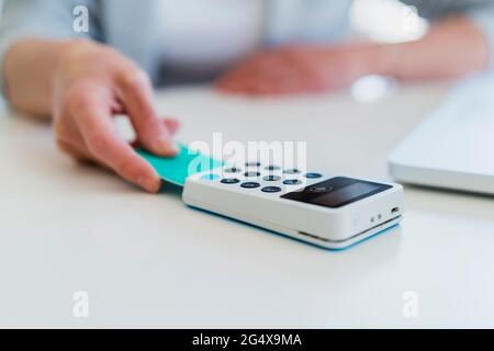 Geschäftsfrau scannt Kreditkarte durch Terminal am Schreibtisch Stockfoto