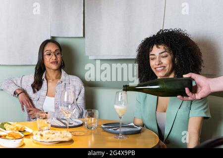 Ein männlicher Kellner, der im Restaurant Getränke aus Glas von Geschäftsfrauen serviert Stockfoto