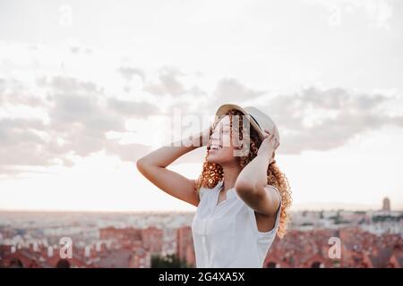 Glückliche hispanische Frau, die einen Hut gegen den Himmel trägt Stockfoto