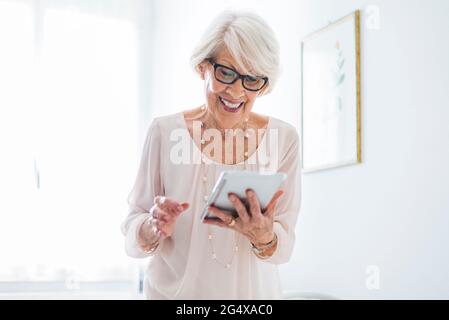 Lächelnde ältere Frau mit digital-Tablette zu Hause Stockfoto