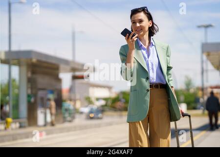 Geschäftsfrau, die am Bahnhof eine Sprachnachricht über ein Smartphone sendet Stockfoto