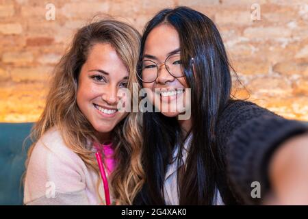 Lächelnde Freundinnen, die in der Bar Selfie machen Stockfoto