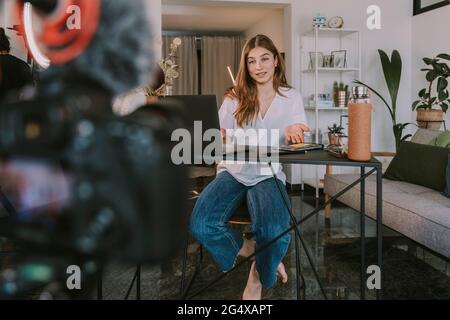 Studentin, die am Schreibtisch sitzt, während sie zu Hause Tutorial macht Stockfoto