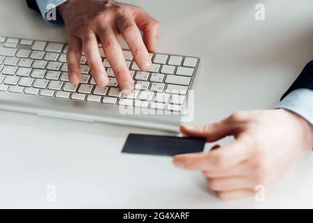 Geschäftsmann hält die Karte, während er im Büro auf der Computertastatur tippt Stockfoto