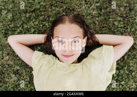 Lächelndes Mädchen, das im Sommer auf Gras liegt Stockfoto