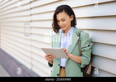 Geschäftsfrau mit digitalem Tablet in Wandnähe Stockfoto