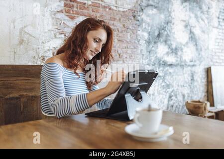 Eine Grafikdesignerin, die im Café ein Tablet benutzt Stockfoto