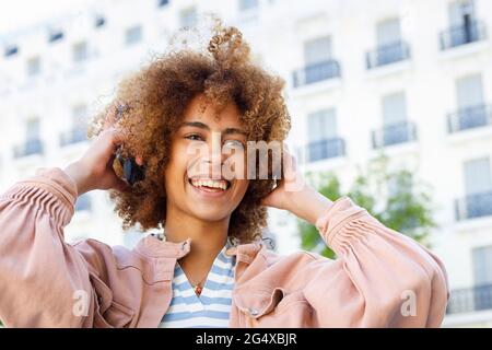 Glückliche junge Frau, die Kopfhörer anpasst Stockfoto