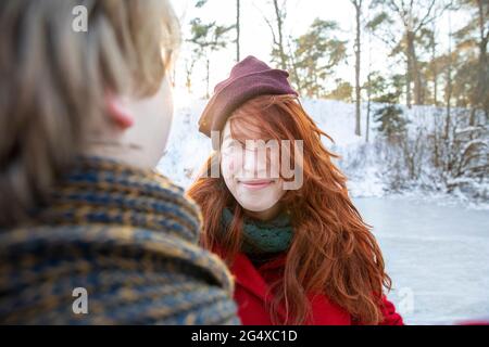 Lächelnde Rothaarige Frau mit Strickmütze, die ihren Freund ansieht Stockfoto