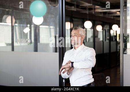 Geschäftsmann mit Armbanduhr wartet vor der Tür im Büro Stockfoto