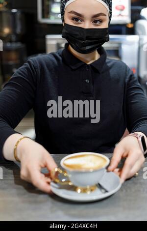 Kellnerin serviert Kaffee, während sie im Café arbeitet Stockfoto