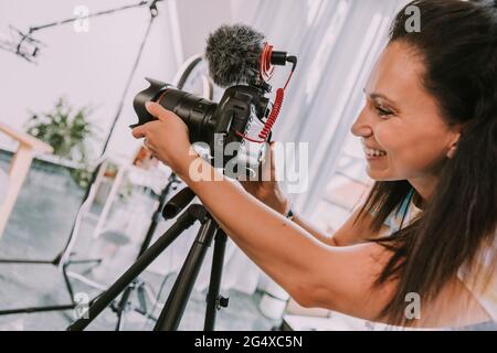 Lächelnde Frau, die die Kamera während der Dreharbeiten im Studio justiert Stockfoto