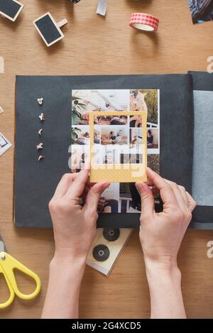 Frau hält Rahmen über Foto auf Scrapbook Stockfoto