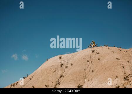 Männlicher Biker, der während eines sonnigen Tages Motorrad auf dem Berg fährt Stockfoto