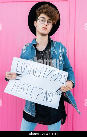 Schwuler Mann, der Gleichberechtigung verlangt, steht vor einer rosa Wand Stockfoto