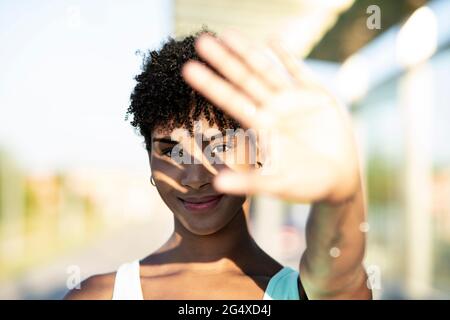 Junge Frau, die die Augen vor Sonnenlicht im Freien schützt Stockfoto