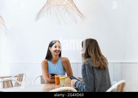 Freundinnen sprechen miteinander, während sie im Café sitzen Stockfoto