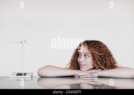 Die lockige Frau starrte das Turbinenmodell an, während sie sich auf den Tisch lehnte Stockfoto