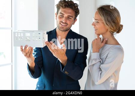 Männliche und weibliche Unternehmer diskutieren über Hausmodell im Büro Stockfoto