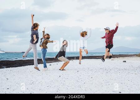 Unbeschwerte Freunde springen am Strand Stockfoto